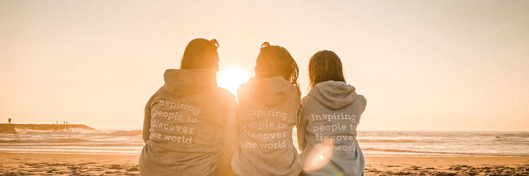 Groep vrienden die op het strand lopen. De middelste man draagt een vrouw op zijn rug.
