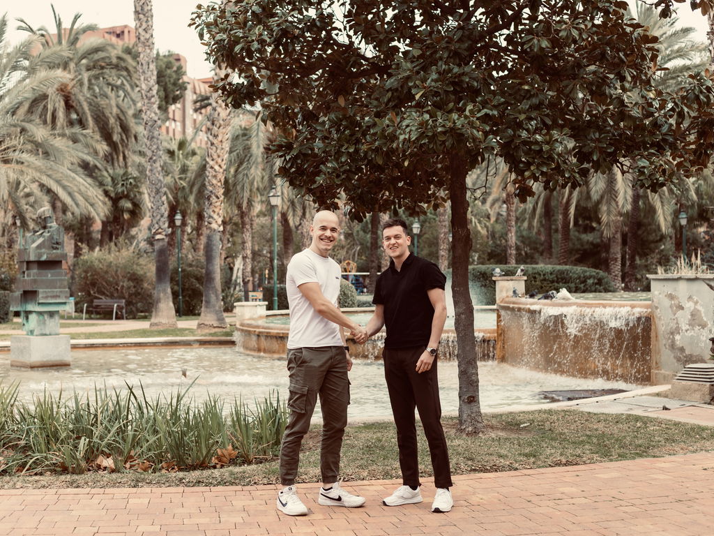 Zwei Männer in einem sonnigen Park in Valencia, die sich die Hand geben